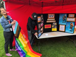 setting up pride flag above hiv information booth